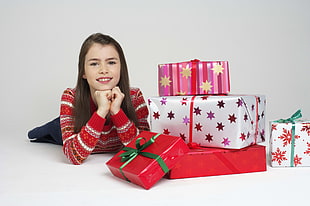 girl in red and white striped sweater beside Christmas gifts